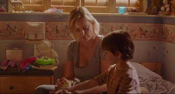 Movie still from “Tully” (2018), directed by Jason Reitman – A woman and a boy are looking at something in a jar; Medium shot, Over the shoulder angle