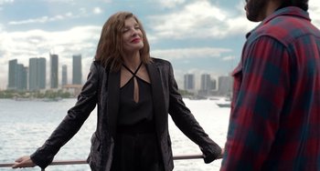 Movie still from “Velvet Buzzsaw” (2019), directed by Dan Gilroy – A woman standing next to a body of water; Medium shot, Over the shoulder angle