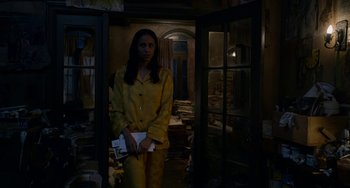 Movie still from “Velvet Buzzsaw” (2019), directed by Dan Gilroy – A woman standing in a room holding a book; Medium shot, High angle