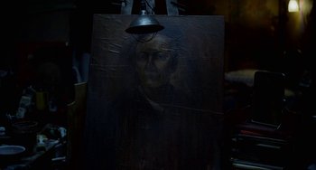Movie still from “Velvet Buzzsaw” (2019), directed by Dan Gilroy – A painting of an old man with a bell hanging from the side of it; Close Up shot, High angle