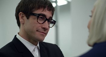 Movie still from “Velvet Buzzsaw” (2019), directed by Dan Gilroy – A person wearing glasses and a suit; Close Up shot, Over the shoulder angle