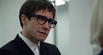 Movie still from “Velvet Buzzsaw” (2019), directed by Dan Gilroy – A person wearing glasses and a suit; Close Up shot, Over the shoulder angle
