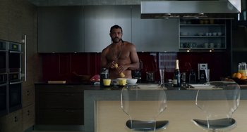 Movie still from “Velvet Buzzsaw” (2019), directed by Dan Gilroy – A man standing at a kitchen counter preparing a meal; Medium shot, Overhead angle