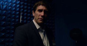 Movie still from “Velvet Buzzsaw” (2019), directed by Dan Gilroy – A man wearing a suit and tie standing in front of a wall; Close Up shot, Low angle