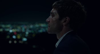 Movie still from “Velvet Buzzsaw” (2019), directed by Dan Gilroy – A person wearing a suit and tie; Close Up shot, Low angle