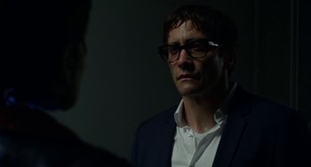 Movie still from “Velvet Buzzsaw” (2019), directed by Dan Gilroy – A man in a suit and glasses looking at another man; Close Up shot, Over the shoulder angle