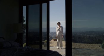 Movie still from “Velvet Buzzsaw” (2019), directed by Dan Gilroy – A woman standing on a balcony looking out a window; Wide shot, Low angle