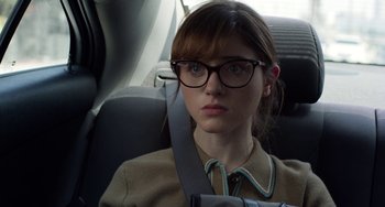 Movie still from “Velvet Buzzsaw” (2019), directed by Dan Gilroy – A woman sitting in the back seat of a car wearing glasses; Close Up shot, Over the shoulder angle