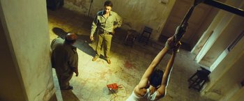 Movie still from “Slumdog Millionaire” (2008), directed by Danny Boyle – A group of people standing around in a room; Wide shot, Low angle