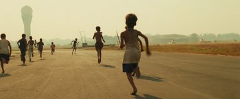 Movie still from “Slumdog Millionaire” (2008), directed by Danny Boyle – A group of people running down a street; Wide shot, High angle