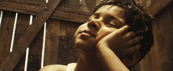 Movie still from “Slumdog Millionaire” (2008), directed by Danny Boyle – A young boy with his head tilted to the side; Close Up shot, Low angle