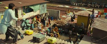 Movie still from “Slumdog Millionaire” (2008), directed by Danny Boyle – A group of people standing on top of a dirt field; Extreme Wide shot, High angle