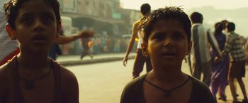 Movie still from “Slumdog Millionaire” (2008), directed by Danny Boyle – A young boy is standing on the side of the street; Close Up shot, Low angle