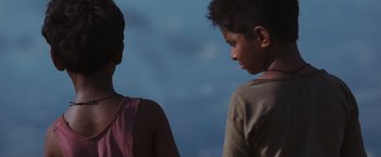Movie still from “Slumdog Millionaire” (2008), directed by Danny Boyle – Two young boys standing next to each other in front of a sky background; Close Up shot, Low angle