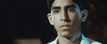 Movie still from “Slumdog Millionaire” (2008), directed by Danny Boyle – A young man's face in a dark room; Close Up shot, Low angle