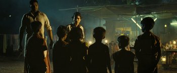 Movie still from “Slumdog Millionaire” (2008), directed by Danny Boyle – A group of people standing in the dark at night; Wide shot, Over the shoulder angle