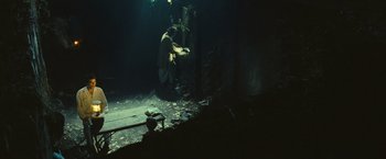 Movie still from “Slumdog Millionaire” (2008), directed by Danny Boyle – A man sitting on the ground in a dark room; Wide shot, High angle