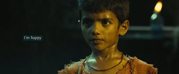 Movie still from “Slumdog Millionaire” (2008), directed by Danny Boyle – A young boy wearing a necklace looks into the camera; Close Up shot, High angle