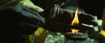 Movie still from “Slumdog Millionaire” (2008), directed by Danny Boyle – A person lighting a candle on a candle holder; Extreme Close Up shot, High angle