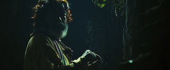 Movie still from “Slumdog Millionaire” (2008), directed by Danny Boyle – A man with a red beard is sitting under a tree; Close Up shot, Low angle