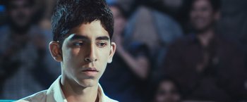 Movie still from “Slumdog Millionaire” (2008), directed by Danny Boyle – A young man is looking into the distance; Close Up shot, Low angle