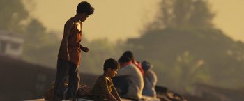 Movie still from “Slumdog Millionaire” (2008), directed by Danny Boyle – A group of people sitting and standing on top of a hill; Wide shot, Low angle