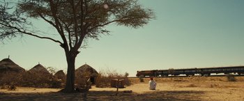 Movie still from “Slumdog Millionaire” (2008), directed by Danny Boyle – A man in a white robe sitting in the sand; Extreme Wide shot, Low angle