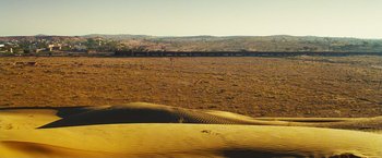 Movie still from “Slumdog Millionaire” (2008), directed by Danny Boyle – A desert landscape with sand dunes in the foreground; Extreme Wide shot, High angle