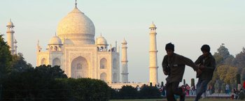 Movie still from “Slumdog Millionaire” (2008), directed by Danny Boyle – A person walking in front of a large building; Extreme Wide shot, Low angle