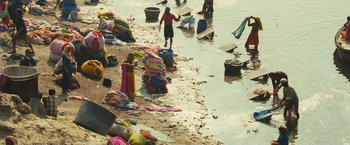 Movie still from “Slumdog Millionaire” (2008), directed by Danny Boyle – A beach filled with lots of towels and clothes; Wide shot, High angle