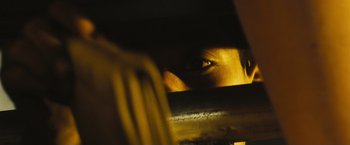 Movie still from “Slumdog Millionaire” (2008), directed by Danny Boyle – A person looking through a hole in the wall; Extreme Close Up shot, Low angle