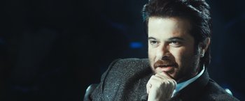 Movie still from “Slumdog Millionaire” (2008), directed by Danny Boyle – A person sitting in a chair with his hand under his chin; Close Up shot, High angle