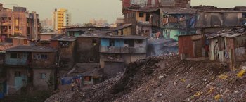 Movie still from “Slumdog Millionaire” (2008), directed by Danny Boyle – A view of a bunch of buildings that are on a hill; Extreme Wide shot, High angle