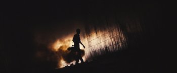 Movie still from “Slumdog Millionaire” (2008), directed by Danny Boyle – A person walking in front of a wall with smoke coming out of it; Wide shot, Low angle