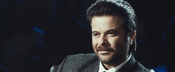 Movie still from “Slumdog Millionaire” (2008), directed by Danny Boyle – A person wearing a suit and tie; Close Up shot, Over the shoulder angle