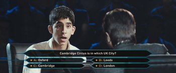 Movie still from “Slumdog Millionaire” (2008), directed by Danny Boyle – A man is sitting in front of a television screen; Close Up shot, High angle