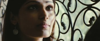 Movie still from “Slumdog Millionaire” (2008), directed by Danny Boyle – A woman's face with a wrought iron gate in the background; Close Up shot, Low angle
