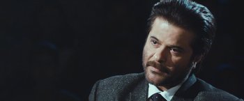 Movie still from “Slumdog Millionaire” (2008), directed by Danny Boyle – A person wearing a suit and tie; Close Up shot, Over the shoulder angle