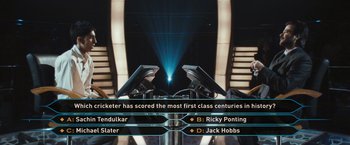 Movie still from “Slumdog Millionaire” (2008), directed by Danny Boyle – A group of people standing next to each other in a room; Wide shot, High angle