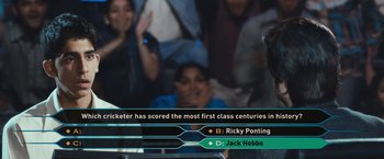 Movie still from “Slumdog Millionaire” (2008), directed by Danny Boyle – A group of people in front of a group of people; Close Up shot, Over the shoulder angle