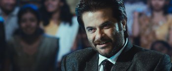 Movie still from “Slumdog Millionaire” (2008), directed by Danny Boyle – A person wearing a suit and tie; Close Up shot, Over the shoulder angle