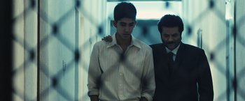 Movie still from “Slumdog Millionaire” (2008), directed by Danny Boyle – A man in a white dress shirt and a man in a black tie; Medium shot, Low angle