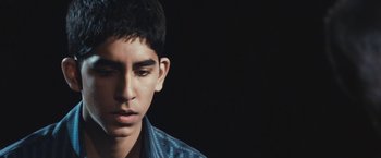 Movie still from “Slumdog Millionaire” (2008), directed by Danny Boyle – A young man in a blue shirt is looking down; Close Up shot, High angle