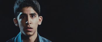 Movie still from “Slumdog Millionaire” (2008), directed by Danny Boyle – A young man is looking into the camera; Close Up shot, Low angle