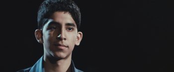 Movie still from “Slumdog Millionaire” (2008), directed by Danny Boyle – A young man is looking into the camera; Close Up shot, Low angle