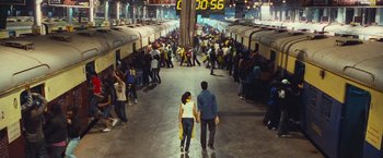 Movie still from “Slumdog Millionaire” (2008), directed by Danny Boyle – Two people are holding hands in a crowded train station; Extreme Wide shot, High angle