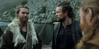 Movie still from “Vikings: Valhalla” (2022), created by Jeb Stuart – Two bearded men standing next to a body of water; Medium shot, Over the shoulder angle