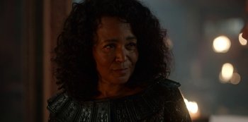 Movie still from “Vikings: Valhalla” (2022), created by Jeb Stuart – An older woman wearing a black and gold outfit; Close Up shot, Over the shoulder angle