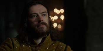 Movie still from “Vikings: Valhalla” (2022), created by Jeb Stuart – A man with long hair and a beard wearing a yellow shirt; Close Up shot, Low angle