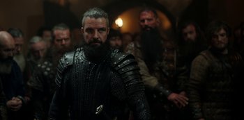 Movie still from “Vikings: Valhalla” (2022), created by Jeb Stuart – A man with a long beard wearing armor; Medium shot, Low angle